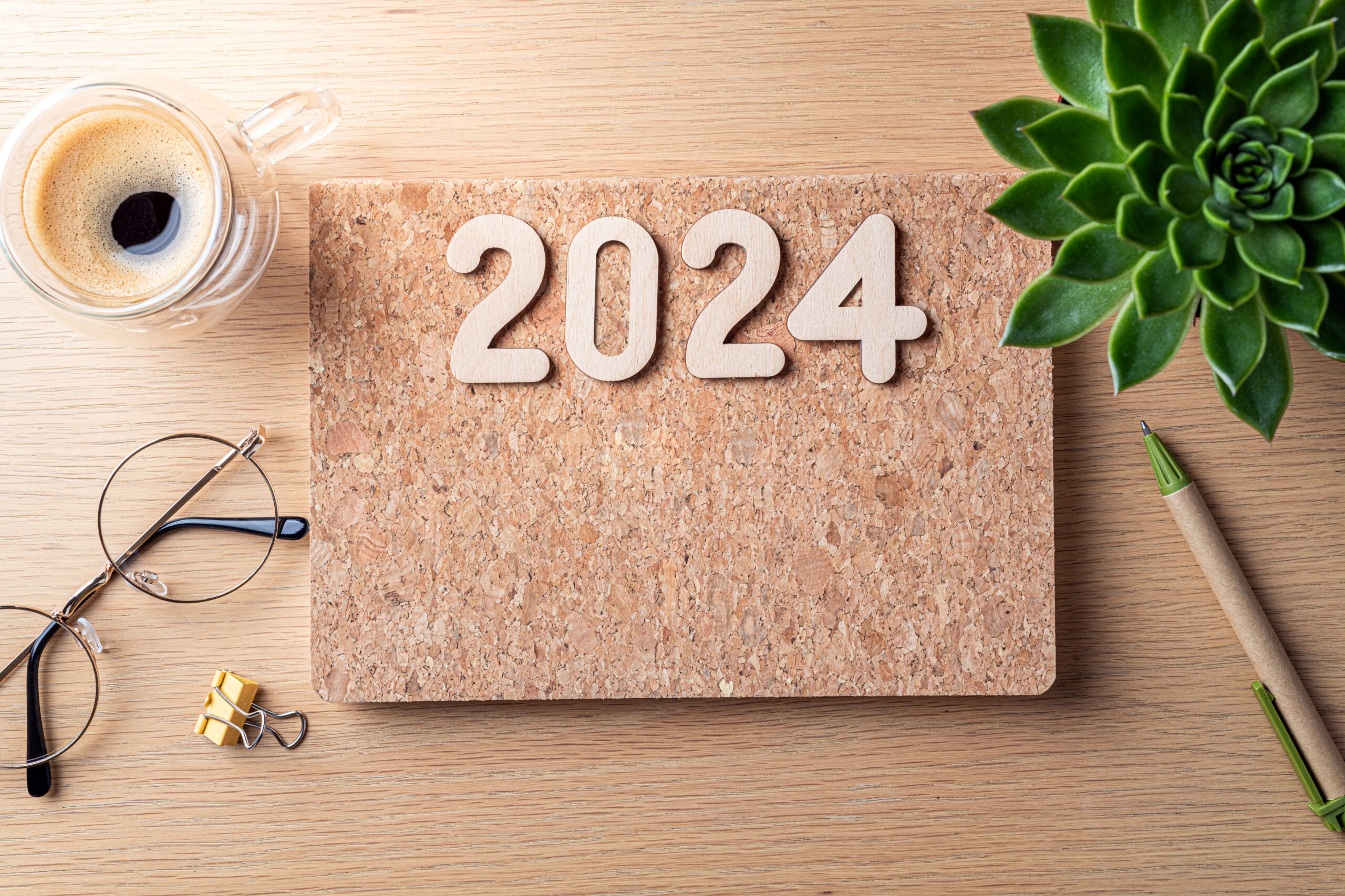 Projet de loi de finance de 2024. Bureau avec carnet, tasse à café, plante sur table en bois.