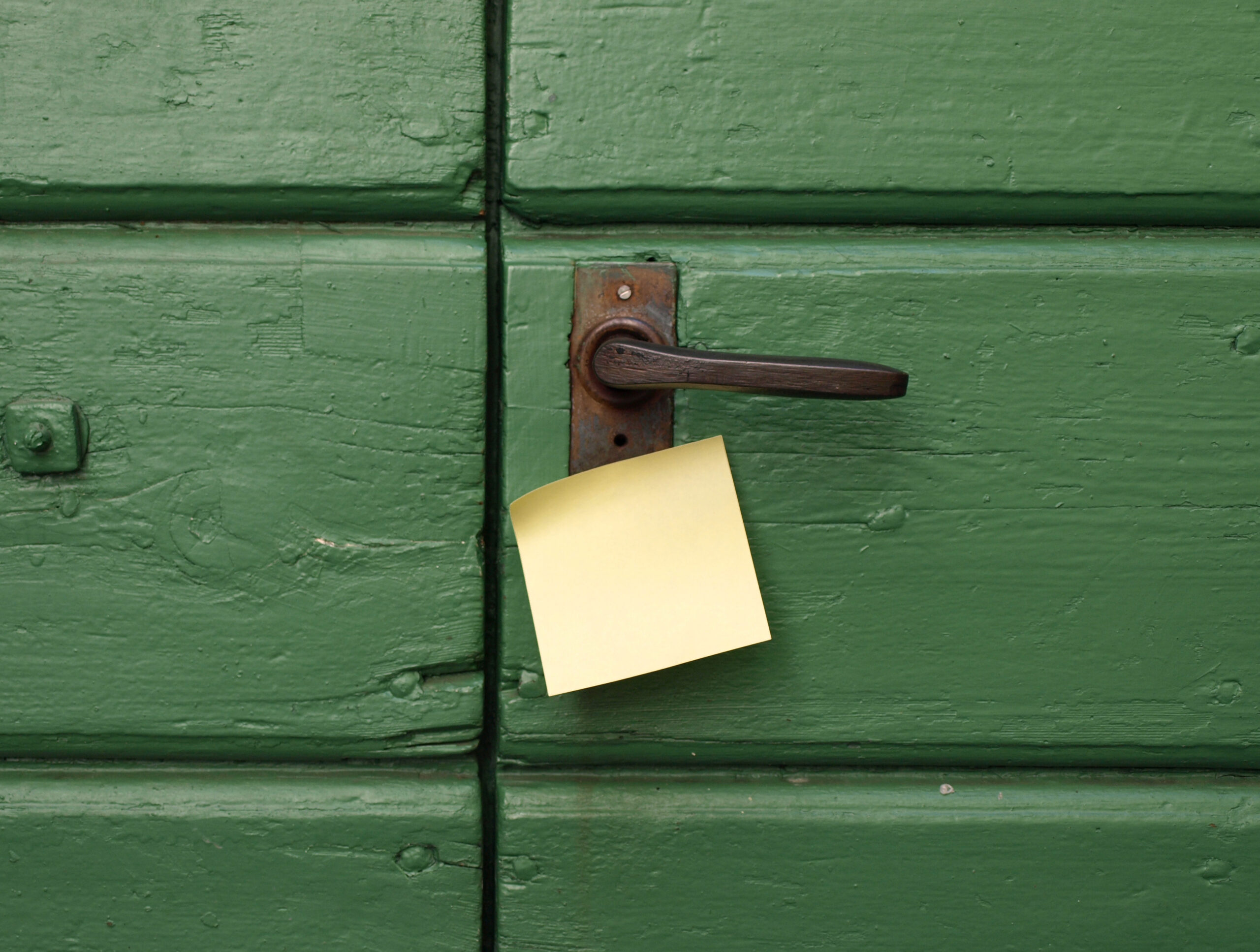 Porte en bois verte avec une poignée de porte noire dont la serrure est cachée par un post-it. Cela illustre la politique de confidentialité de LUCYA Conseil et Patrimoine